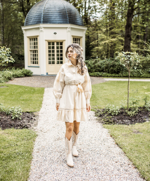 zandkleurig katoenen jurkje met kantdetails staan